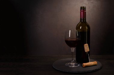 Şarap şişesi, kırmızı şarap ile cam ve tirbuşon koyu ahşap arka plan üzerinde mantar. Kutlama kavramı. Kopya alanı