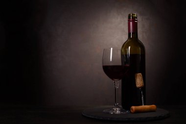 Şarap şişesi, kırmızı şarap ile cam ve tirbuşon koyu ahşap arka plan üzerinde mantar. Kutlama kavramı. Kopya alanı