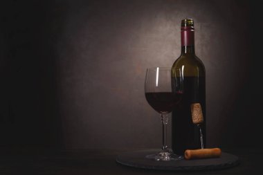 Şarap şişesi, kırmızı şarap ile cam ve tirbuşon koyu ahşap arka plan üzerinde mantar. Kutlama kavramı. Uzay kopyalayın. Tonda