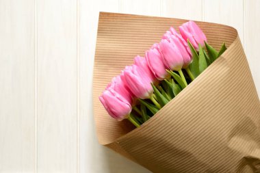 Beyaz ahşap zemin üzerinde güzel pembe lale buketi. Üstten görünüm. Kopya alanı