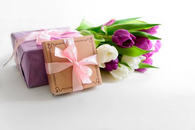 Buket beyaz ve mor laleler, hediye kutusu ve boş kağıt beyaz ahşap zemin üzerinde. Üstten görünüm. Düz yatıyordu. Kopya alanı.