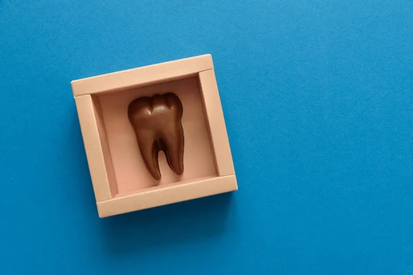 青い紙の背景にボックスのチョコレートから歯します 平面図です 領域をコピーします 健康な歯や歯科医療コンセプト — ストック写真