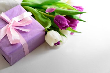Beyaz ve mor laleler ve hediye kutusu beyaz ahşap zemin üzerinde buket. Üstten görünüm. Düz yatıyordu. Uzay kopyalayın. Sevgililer günü, anneler günü, Doğum günü, düğün kutlama kavramı.