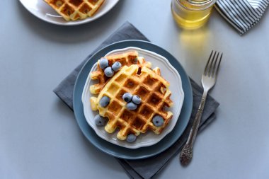 Belçika Waffle yaban mersini ve ballı gri ahşap zemin üzerinde. Ev yapımı sağlıklı kahvaltı. Seçici odak