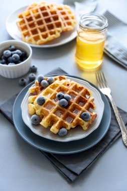 Belçika Waffle yaban mersini ve ballı gri ahşap zemin üzerinde. Ev yapımı sağlıklı kahvaltı. Seçici odak