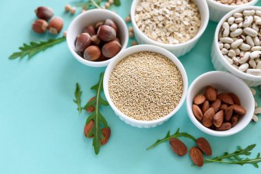 Organik quinoa, mercimek, nohut, buğday, ceviz, badem, fındık ve susam ile kase ayarlayın. Tahıllar ve baklagiller ürün yelpazesine mavi Kağıt arka plan üzerinde. Üstten görünüm. Uzay kopyalayın. Düz yatıyordu