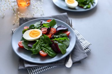 Salata karışımı ile ıspanak, roka, pancar yaprakları, domates ve gri ahşap arka plan üzerinde yumurta. Vejetaryen yiyecekler kavramı. Seçici odak.