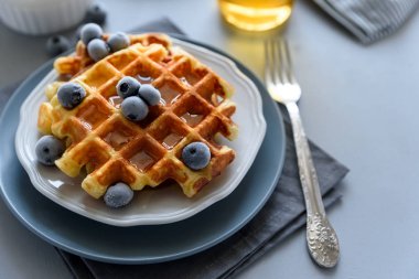 Belçika Waffle yaban mersini ve ballı gri ahşap zemin üzerinde. Ev yapımı sağlıklı kahvaltı. Seçici odak