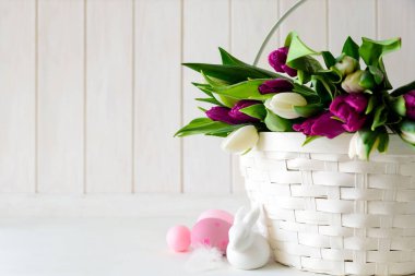 Beyaz ve mor laleler, Paskalya yumurtaları ve tavşan'Beyaz ahşap arka plan ile sepet. Kopya alanı