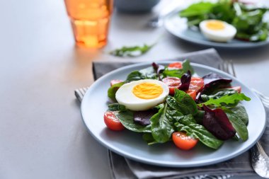 Salata karışımı ile ıspanak, roka, pancar yaprakları, domates ve gri ahşap arka plan üzerinde yumurta. Vejetaryen yiyecekler kavramı. Seçici odak.