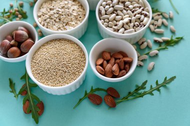 Organik quinoa, mercimek, nohut, buğday, ceviz, badem, fındık ve susam ile kase ayarlayın. Tahıllar ve baklagiller ürün yelpazesine mavi Kağıt arka plan üzerinde. Üstten görünüm. Uzay kopyalayın. Düz yatıyordu