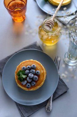 Dondurulmuş yaban mersini ve gri arka plan üzerinde ballı krep yığını. Seçici odak