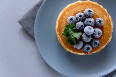 Dondurulmuş yaban mersini ve gri arka plan üzerinde ballı krep yığını. Seçici odak