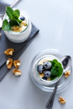 Chia tohum puding granola, yaban mersini, cevizli ve ballı nane yaprakları gri arka plan üzerine dekore edilmiştir. Seçici odak. Sağlıklı beslenme veya Vejetaryen yiyecekler kavramı