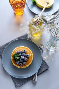 Dondurulmuş yaban mersini ve gri arka plan üzerinde ballı krep yığını. Seçici odak