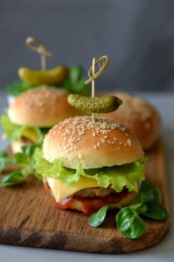 Marul, ketçap, peynir ve gri ahşap arka plan üzerinde tavuk lezzetli ev yapımı hamburger. Kopya alanı