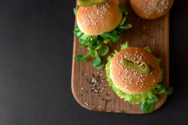 Marul, ketçap, peynir ve kahverengi ahşap zemin üzerinde tavuk lezzetli ev yapımı hamburger. Kopya alanı