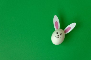 Paskalya tavşanı yumurta ve yeşil pastel renkli kağıt kulaklara yapılmıştır. Yaratıcı bir fikir. Sanat gıda kavramı. Düz yatıyordu. Üstten Görünüm