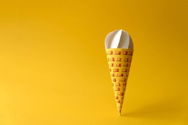 Kağıt vanilyalı dondurma külahı Sarı zemin üzerine. Uzay kopyalayın. Yaratıcı ya da sanat gıda kavramı