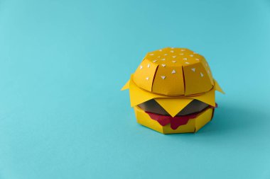 Sığır eti, peynir ve sos mavi bir arka plan üzerinde kağıt çizburger. Uzay kopyalayın. Yaratıcı ya da sanat gıda kavramı