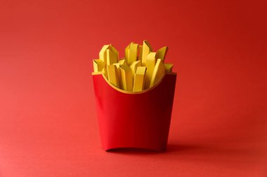 Kağıt patates kızartması kırmızı zemin üzerine kırmızı karton kutuda. Uzay kopyalayın. Yaratıcı ya da sanat gıda kavramı