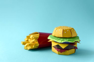 Sığır eti, peynir, domates, marul, soğan, pastırma ve kişiler üzerine mavi arka plan ile kutu kağıt çizburger. Uzay kopyalayın. Yaratıcı veya sanat