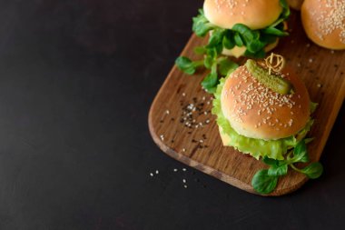 Marul, ketçap, peynir ve kahverengi ahşap zemin üzerinde tavuk lezzetli ev yapımı hamburger. Kopya alanı