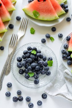 Yaz karpuz dilimleri, yaban mersini ve nane ile plakalar gri plaka üzerinde bırakır. Sağlıklı beslenme kavramı. Üstten Görünüm