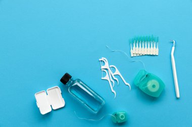 Mavi arka plan üzerinde diş bakımı için farklı araçlar. Diş fırçası, temizleyici, ipi, flossers, diş telleri ve interdental fırça için balmumu. Üstten Görünüm. Düz yatıyordu. Dişlerle ilgili sağlık bilgisi ve bakım kavramı