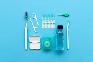 Mavi arka plan üzerinde diş bakımı için farklı araçlar. Diş fırçası, temizleyici, ipi, flossers, diş telleri ve interdental fırça için balmumu. Üstten Görünüm. Düz yatıyordu. Dişlerle ilgili sağlık bilgisi ve bakım kavramı