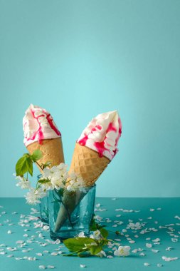 Meyve şurubu ile eritme Dondurma külahı mavi zemin üzerine beyaz kiraz çiçeği dekore edilmiştir.