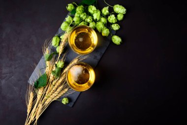 Bardak bira yeşil atlama ve koyu ahşap arka plan buğday kulaklara. Natürmort. Üstten Görünüm. Kopya alanı