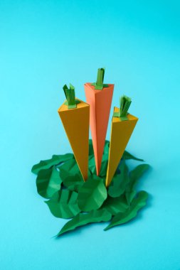 Havuç, ıspanak ve roka yaprakları yapılmış kağıt üzerinde mavi arka plan. Taze sebze. En az, yaratıcı, vegan, sağlıklı veya gıda sanat kavramı. Uzay kopyalayın. Üstten Görünüm