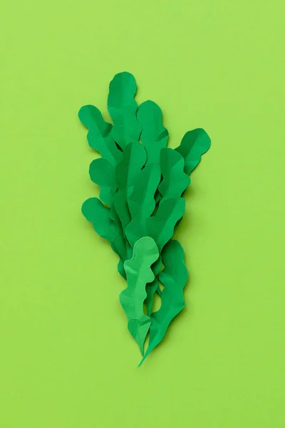 Arugula leaves made from paper on green background. Minimal, creative, vegan, healthy or food art concept. Flat lay. Top view