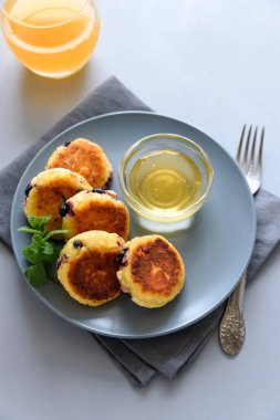 Yaban mersini, bal, reçel ve kahve ile süzme peynir krep. Ukrayna syrniki, süzme peynir börek veya gri ahşap arka planda krep. Sağlıklı yeme konsepti. Seçici odak