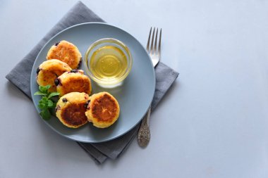 Yaban mersini, bal, reçel ve kahve ile süzme peynir krep. Ukrayna syrniki, süzme peynir börek veya gri ahşap arka planda krep. Sağlıklı yeme konsepti. Seçici odak