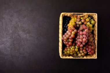 Koyu ahşap arka plan üzerinde rustik sepet olgun üzüm dalları. Üst te. Kopya alanı. Hasat ve sağlıklı beslenme konsepti