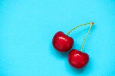 Mavi arka planda iki kırmızı olgun kiraz böğürtlen. Düz yatıyordu. Sağlıklı gıda kavramı.