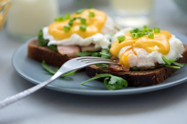 Arugula, pastırma ve gri ahşap arka plan üzerinde hollandaise sos ile yumurta Benedict kapatın. Yumuşak odak. Sağlıklı beslenme konsepti