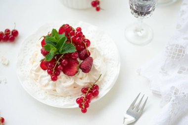 Beyaz arka plan üzerinde çilek, ahududu, kırmızı frenk üzümü ve nane yaprakları ile Pavlova meyve kek. Seçici odak. Sağlıklı gıda kavramı