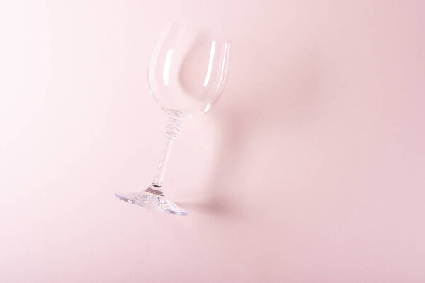 Single empty wineglass lying on pink background. Wine degustation concept. Flat lay. Top view. Copy space