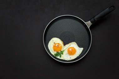Arugula yaprakları ile tavada kızarmış yumurta, siyah ahşap arka plan üzerinde kahvaltı için tuz ve biber. Üst te. Düz yatıyordu. Kopya alanı. Sağlıklı gıda kavramı
