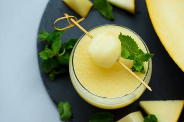 Kavun topu ve nane gri ahşap arka planda yaprakları ile soğuk taze kavun Smoothie. Yaz içeceği. Sağlıklı gıda konsepti. Yumuşak odaklanma. Üst görünüm