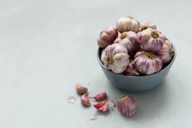 Sarımsak karanfil ve ampuller gri ahşap arka plan üzerinde kase. Hasat konsepti