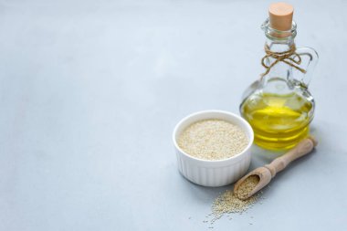 Şişe cam susam yağı ve gri ahşap arka plan üzerinde tohum. Kopya alanı. Yumuşak odaklama.