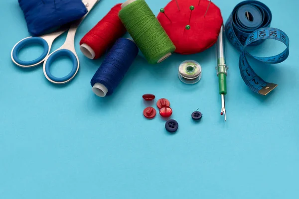 五颜六色的缝纫配件 纽扣和缝纫胶带的蓝色背景 顶部视图 — 图库照片