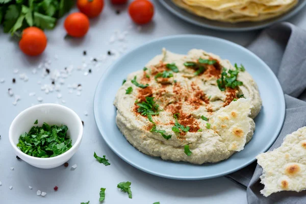 Patlıcan daldırma baba ganoush (mutabbal) otlar ve gri ahşap arka plan üzerinde kırmızı biber ile. Seçici odak. Geleneksel arap yemekleri