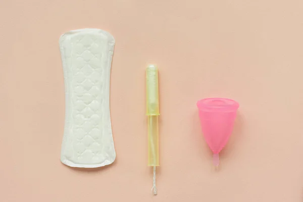 Sanitary napkins or pad, tampon and menstrual cup on pink background. Female intimate hygiene concept. Top view. Copy space.