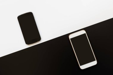 Beyaz arka planda siyah ve siyah akıllı telefonlar. Kişisel aksesuarların üst görünümü.
