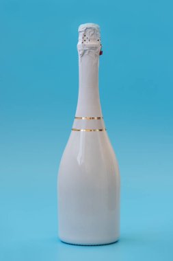 Mavi arka planda şampanya şişesi. Doğum günü ve yeni yıl kutlaması konsepti. Ön manzara. Model.
